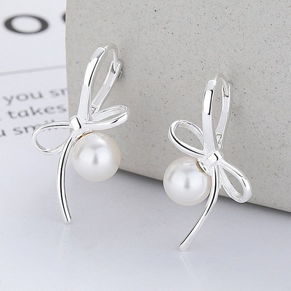 Pearl Earrings close-up with geometric bow and lustrous pearl on stone block