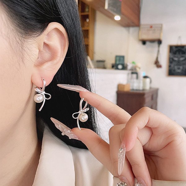 Pearl Earrings worn on ear showing sculpted bow and pearl drop in 925 silver