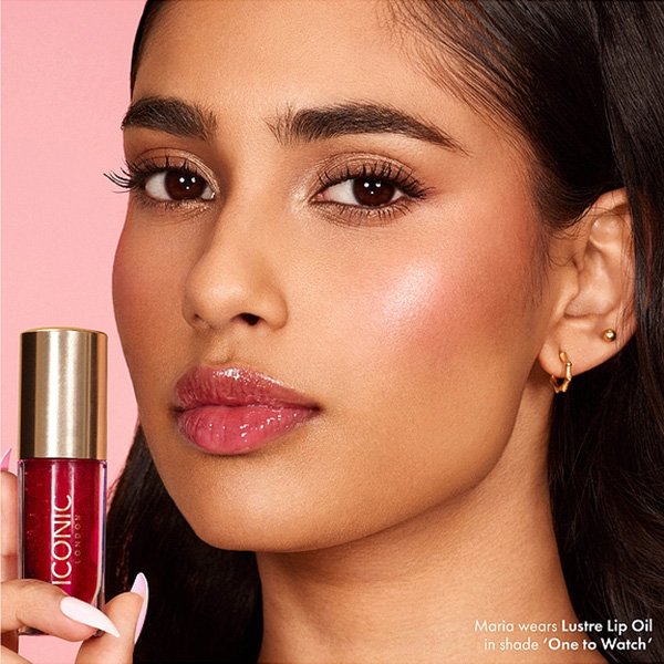 Hydrating Lip Gloss ICONIC LONDON sheer red glossy lips with model holding gold-capped tube