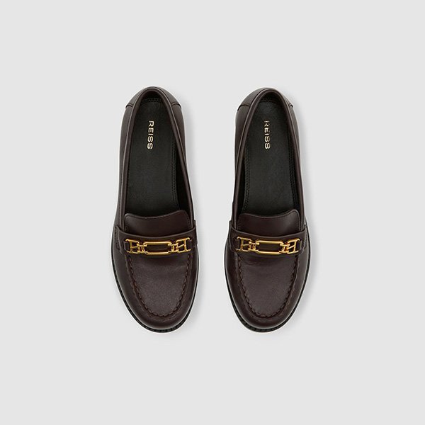 Top view of REISS Rita Chocolate Loafers pair showing gold-tone hardware and REISS branding inside